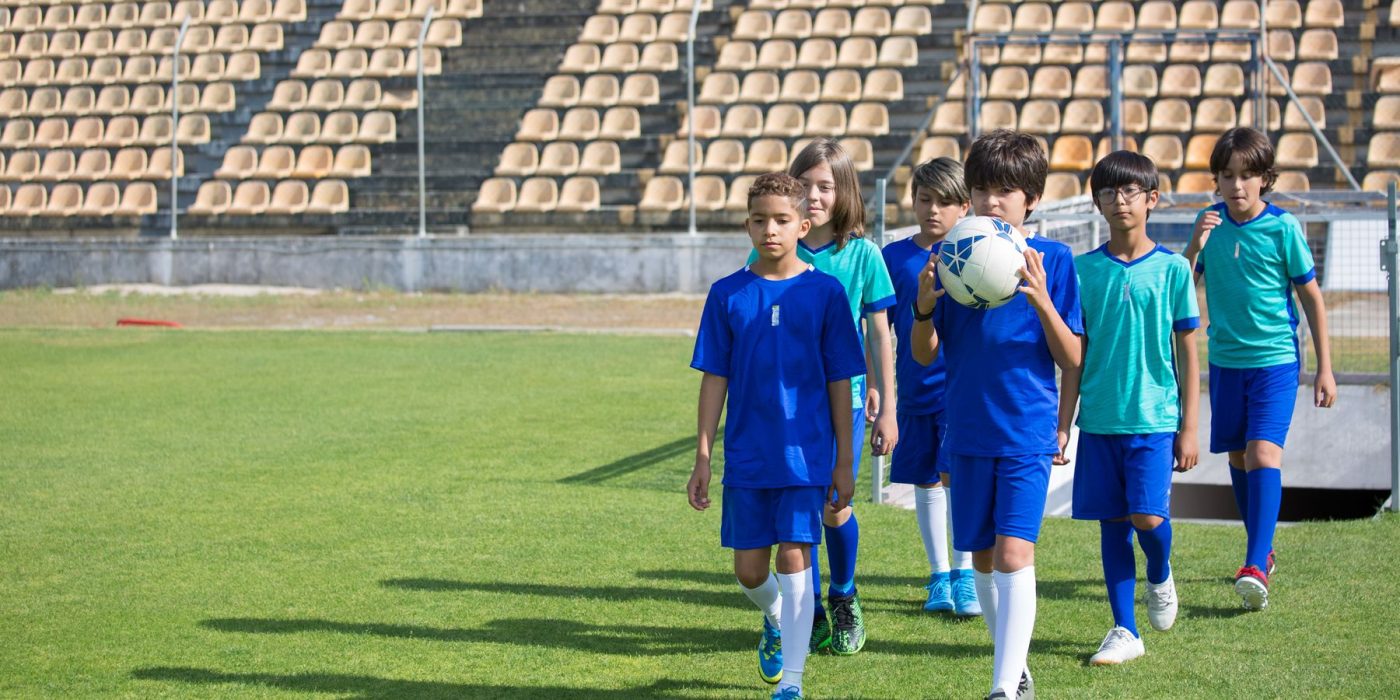 Kinder beim Fußballtraining am Ballfangzaun