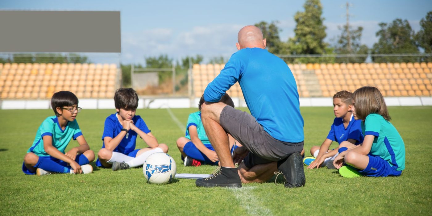 Trainer bespricht sich mit der Jugendmannschaft am Spielfeldrand