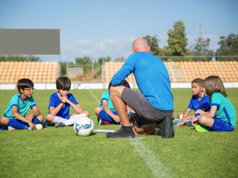 Trainer bespricht sich mit der Jugendmannschaft am Spielfeldrand